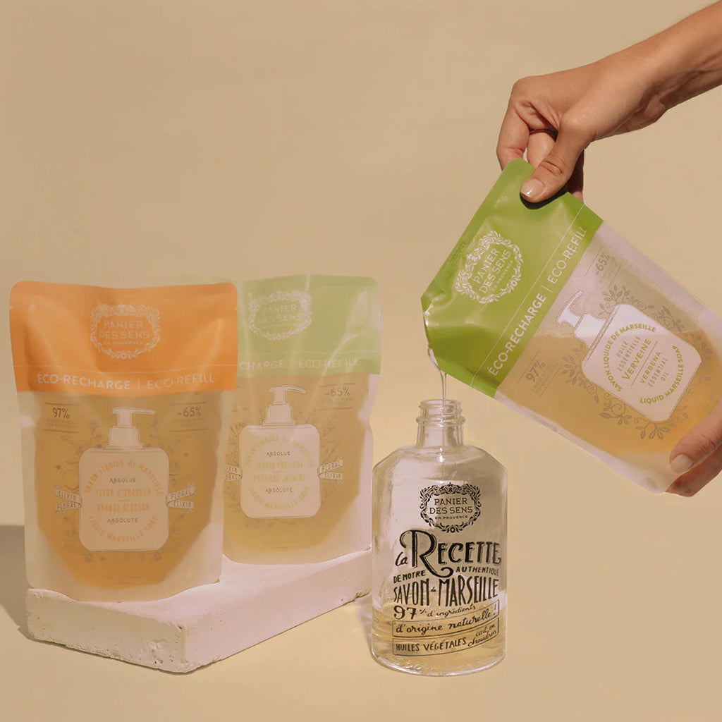 Panier des Sens Verbena Liquid Hand Soap refill bag being poured into a reusable glass bottle.