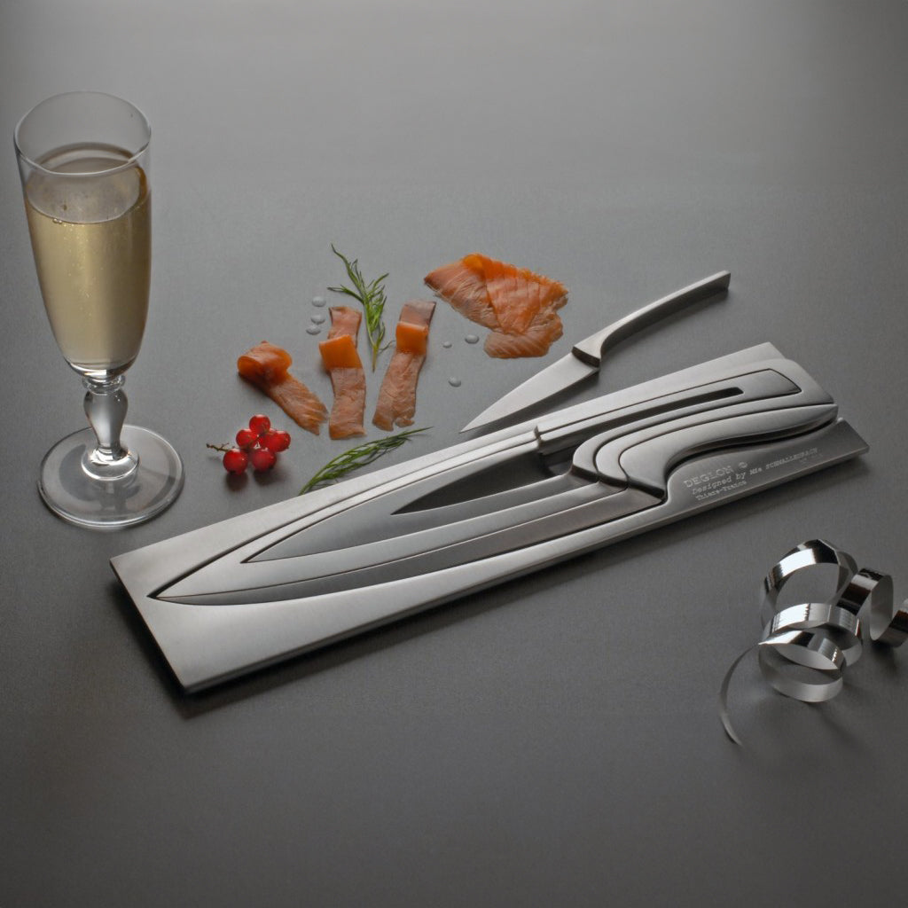 Delgon Stainless Steel Meeting Puzzle Knife resting on a table with a glass of champagne.
