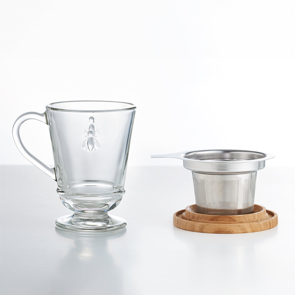 La Rochere Glass Bee Mug positioned next to tea infuser and mug lid.